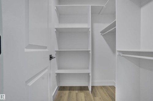 Closet with built-in shelving, multiple hanging rods, and wood-finish flooring - 1915 164 Street, Edmonton, AB 