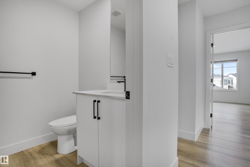 Powder room featuring a white single-sink vanity with a light-toned countertop, matte black faucet, and matching hardware - 1915 164 Street, Edmonton, AB 