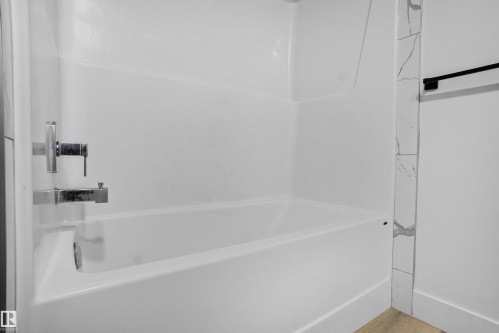 White bathtub with chrome fixtures and surrounding white wall panels - 1915 164 Street, Edmonton, AB 
