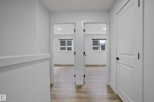White interior doors with matte black hardware, wood-finish flooring, recessed lighting, and white trim - 1915 164 Street, Edmonton, AB 
