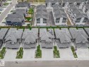 Contemporary residential neighborhood featuring a collection of detached homes and townhomes with gray shingle roofs, private driveways, and landscaped front yards - 1915 164 Street, Edmonton, AB 