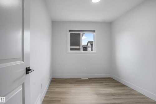 Bright room featuring light wood-finish flooring and a contemporary overhead light fixture - 1915 164 Street, Edmonton, AB 
