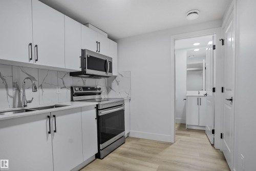 Modern kitchen with white cabinetry and stainless steel appliances - 1915 164 Street, Edmonton, AB 