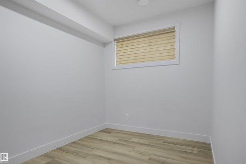 Bright interior room featuring light wood-finish flooring, white baseboards, and a window with horizontal blinds - 1915 164 Street, Edmonton, AB 