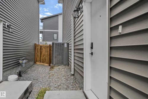 Entryway featuring a white door with smart lock hardware, a wall-mounted exterior light fixture, and horizontal siding - 1915 164 Street, Edmonton, AB 