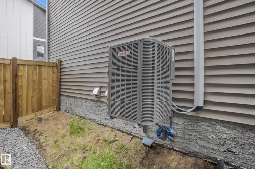 Side exterior with horizontal siding, a substantial air conditioning unit, and a wooden privacy fence - 1915 164 Street, Edmonton, AB 