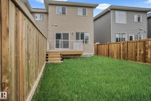 Spacious backyard featuring a wooden deck with white railings, a three-step staircase, and a generously sized lawn - 1915 164 Street, Edmonton, AB 