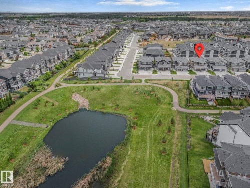 Aerial perspective showcasing a residential development with a large pond and green spaces - 1915 164 Street, Edmonton, AB 