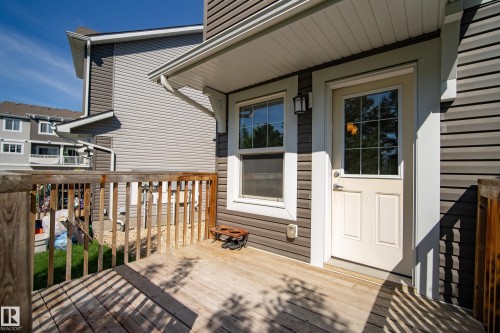 Private wood deck with a full-light panel door, exterior wall lantern, and horizontal siding - 11 4205 30 Street, Edmonton, AB 