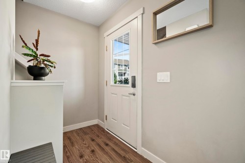 Entryway featuring wood-finish flooring, light grey wall tones, and white baseboards - 11 4205 30 Street, Edmonton, AB 