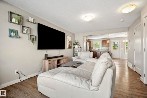 Spacious living area featuring wood-finish flooring, neutral wall tones, and recessed ceiling lighting - 11 4205 30 Street, Edmonton, AB 