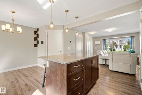 Central kitchen island featuring a granite countertop and dark wood-finish cabinetry - 11 4205 30 Street, Edmonton, AB 