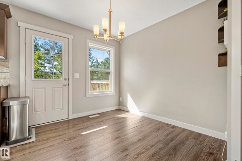 Dining area featuring wood-finish flooring, a contemporary chandelier, and light gray walls - 11 4205 30 Street, Edmonton, AB 