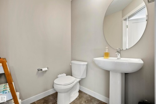 Pedestal sink with chrome faucet, oval mirror, and neutral wall paint - 11 4205 30 Street, Edmonton, AB 