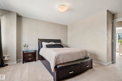 Carpeted bedroom featuring a flush mount ceiling light, neutral wall colors, and white baseboards - 11 4205 30 Street, Edmonton, AB 
