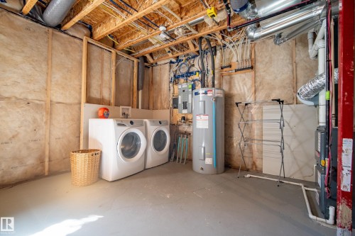 Utility area with exposed structural elements, featuring a water heater, washer, and dryer - 11 4205 30 Street, Edmonton, AB 