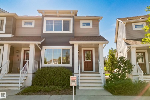 Townhome exterior featuring horizontal siding in two tones, white trim, and a brown shingled roof - 11 4205 30 Street, Edmonton, AB 