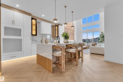 Contemporary kitchen island featuring a waterfall countertop, recessed lighting, and wood-finish paneling - 