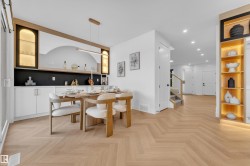 Open-concept dining area featuring herringbone wood-finish flooring, a built-in buffet with custom cabinetry, an integrated arched niche, and a linear pendant light - 