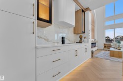 Contemporary kitchen cabinetry featuring white flat-panel doors and drawers with gold-toned hardware - 