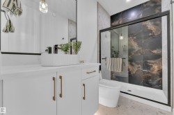 Contemporary bathroom featuring a white vanity with bronze hardware, a vessel sink, and a black framed mirror - 