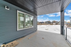 Covered concrete patio with a ribbed metal ceiling, contemporary glass railing, and durable horizontal siding - 
