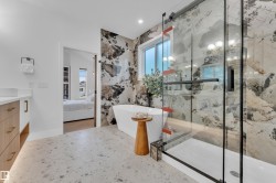 Contemporary bathroom featuring a freestanding tub, a large walk-in shower with a glass enclosure, and a full wall of distinctive patterned tile - 