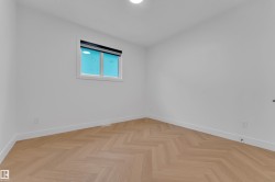 Neutral interior featuring light wood-finish herringbone flooring and white walls - 