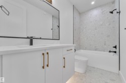 Modern bathroom featuring a white vanity with gold-toned hardware, a rectangular undermount sink, and a matte black faucet - 