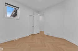 Light wood-finish flooring in a herringbone pattern with white baseboards - 