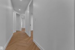 Hallway featuring herringbone wood-finish flooring, recessed lighting, white walls, and white trim - 