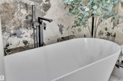 Freestanding soaking tub with a reeded exterior texture and matte black floor-mounted faucet - 