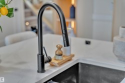 Matte black gooseneck faucet with an integrated sprayer, set within a light-toned countertop, and a dark undermount sink - 