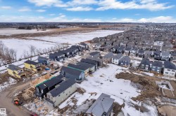 Aerial perspective showcasing a developing residential neighborhood with a mix of completed homes, homes under construction, and undeveloped land - 