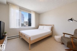 Bright bedroom featuring a large window with urban city buildings visible - 