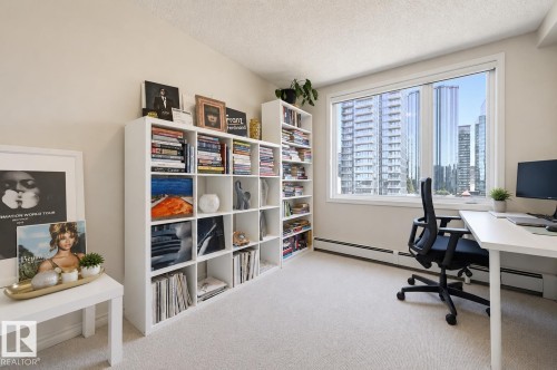 Room featuring a large window, light-toned carpeting, and multiple built-in shelving units - 1103 10180 104 Street, Edmonton, AB 