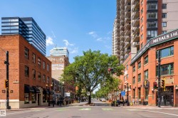 Urban streetscape featuring brick storefronts, mature street trees, and a mix of historic and contemporary architecture - 