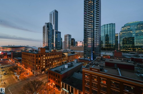 Urban skyline featuring numerous high-rise buildings with contemporary glass and steel facades, alongside lower-rise brick structures with illuminated windows - 1103 10180 104 Street, Edmonton, AB 