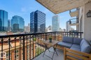 Private balcony featuring a black wrought-iron railing with ornate detailing, concrete flooring, and an exterior wall lantern - 1103 10180 104 Street, Edmonton, AB 