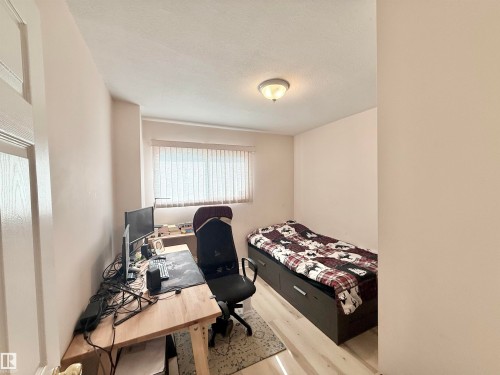 Room featuring light-toned walls, wood-finish flooring, a window with horizontal blinds, and a flush-mount ceiling light fixture - 11941 78 Street, Edmonton, AB 
