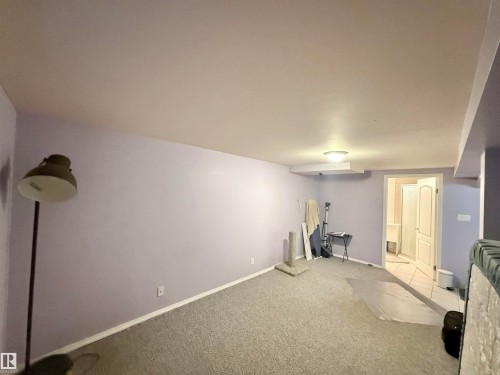 Carpeted room with lavender walls featuring a white baseboard trim - 11941 78 Street, Edmonton, AB 