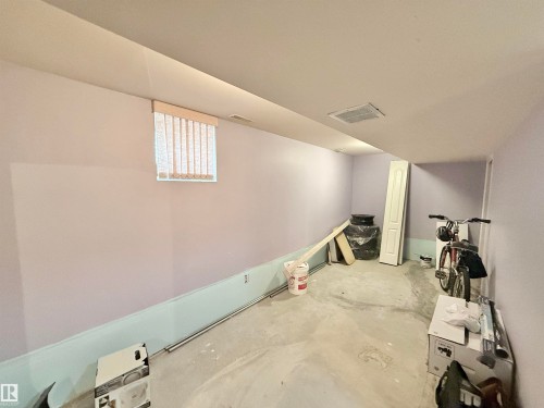 Unfinished basement space featuring a small window with vertical blinds, painted walls, and a concrete floor - 11941 78 Street, Edmonton, AB 