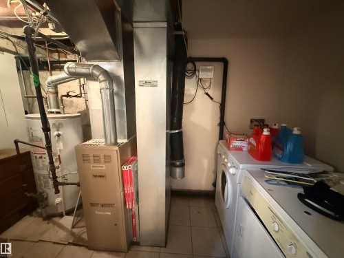 Utility area featuring a water heater, furnace, and a stacked washer and dryer - 11941 78 Street, Edmonton, AB 