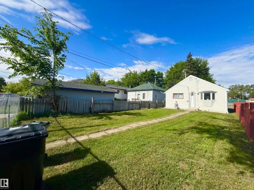 Expansive grassy yard with a concrete pathway leading to the main structure - 11941 78 Street, Edmonton, AB 
