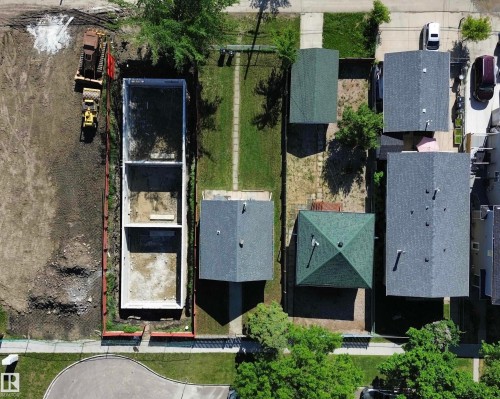 Property featuring an excavated foundation, perimeter fencing, mature trees, and a concrete curb - 11941 78 Street, Edmonton, AB 