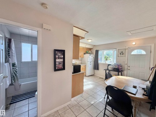 Kitchen featuring light wood cabinetry, white appliances, and a tiled floor - 11941 78 Street, Edmonton, AB 