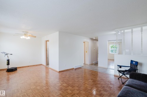 Spacious living area featuring parquet wood-finish flooring, white walls, and a ceiling fan with integrated lighting - 212 Homestead Crescent, Edmonton, AB 