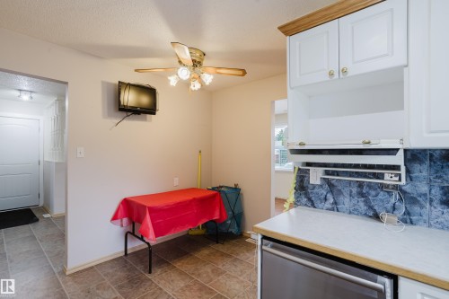 Kitchen area featuring white cabinetry, a dark grey tile backsplash, and a light-colored countertop - 212 Homestead Crescent, Edmonton, AB 