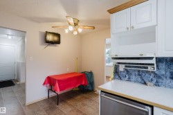 Kitchen area featuring white cabinetry, a dark grey tile backsplash, and a light-colored countertop - 