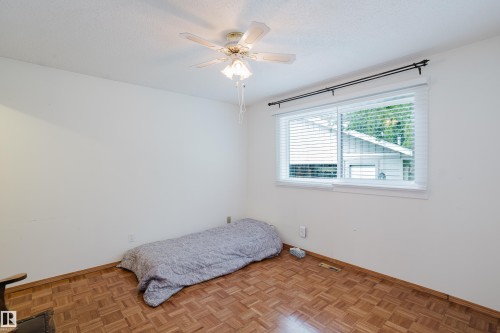 Bright room featuring a ceiling fan with light fixture, a large window with white blinds and curtain rod, and wood-finish parquet flooring - 212 Homestead Crescent, Edmonton, AB 